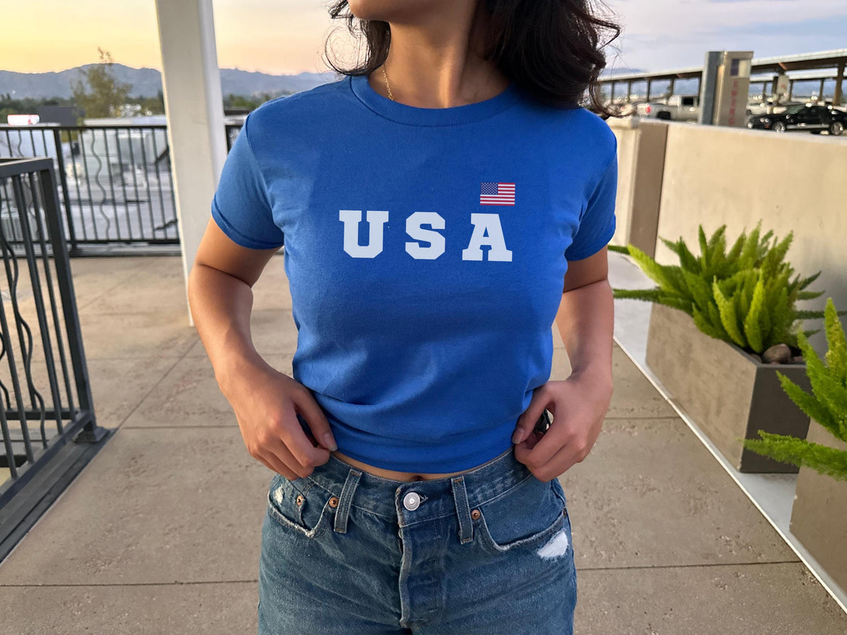 Navy fitted baby tee with bold USA lettering and small American flag graphic