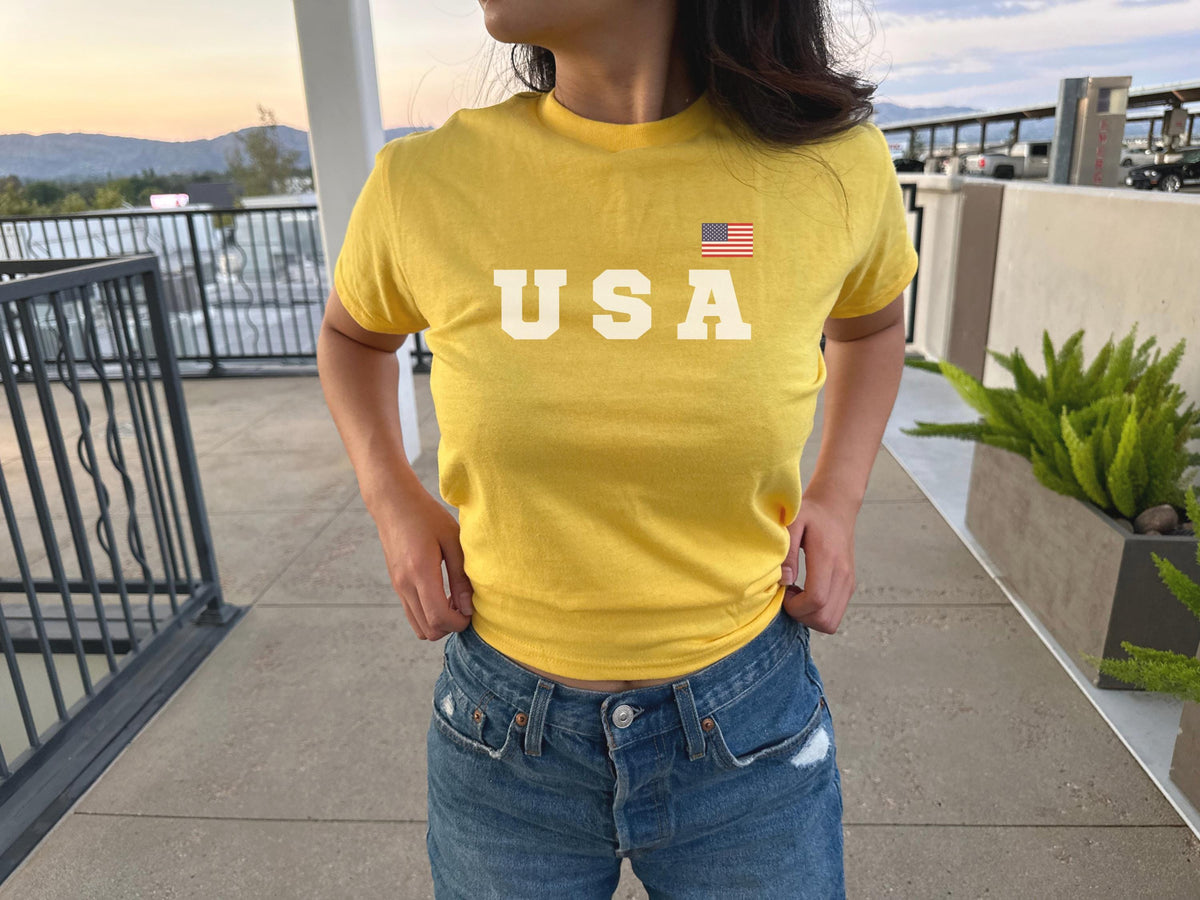 Navy fitted baby tee with bold USA lettering and small American flag graphic