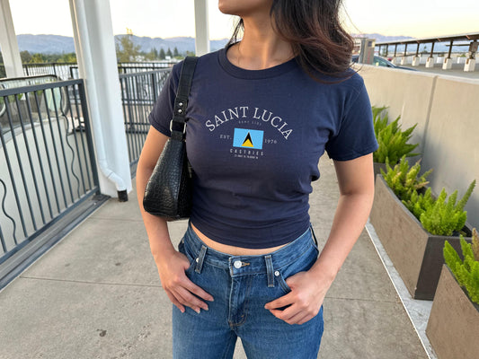 Navy baby tee with arched Saint Lucia text, flag graphic, Sent Lisi, Castries, and Est. 1976 details