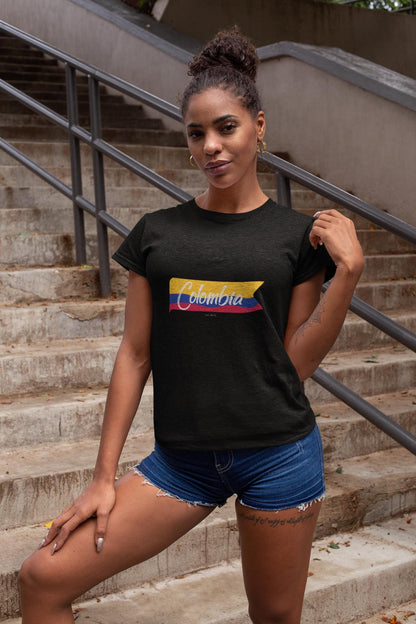 Colombia baby tee with white script over a yellow, blue, and red flag ribbon design.