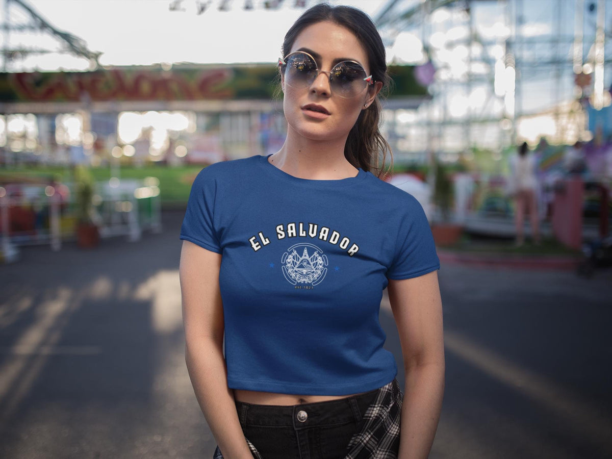 Blue baby tee with El Salvador lettering, emblem graphic, stars, and est. 1821 detail