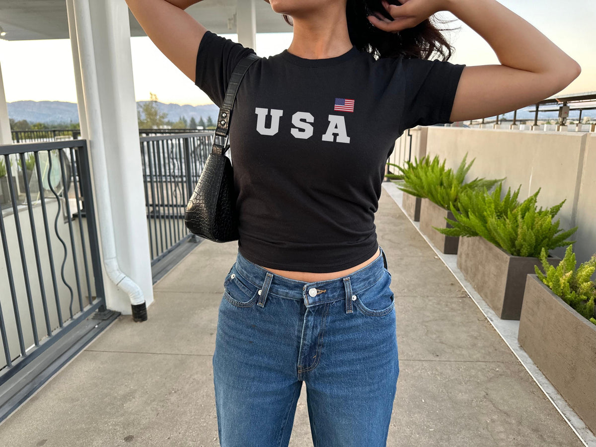 Navy fitted baby tee with bold USA lettering and small American flag graphic