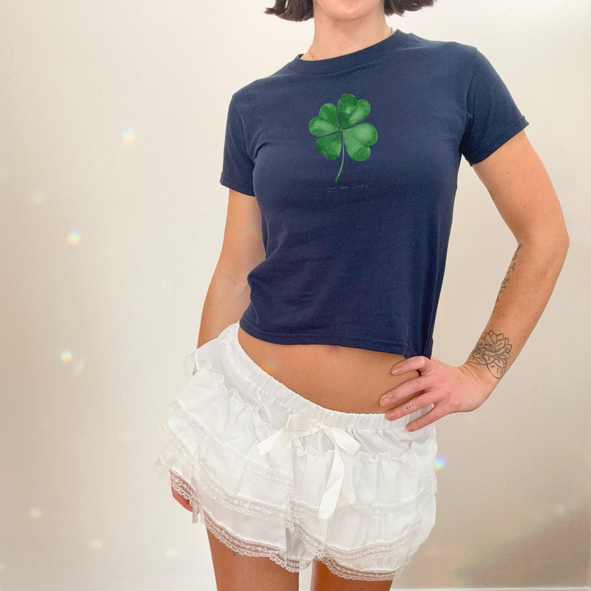 White baby tee with green four leaf clover artwork and small You are lucky text