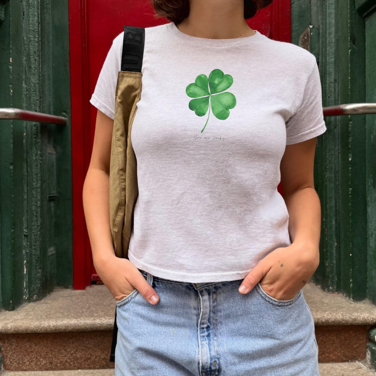 White baby tee with green four leaf clover artwork and small You are lucky text