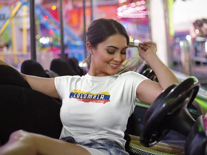 White baby tee with Colombia wordmark over yellow, blue, and red flag brush stroke design