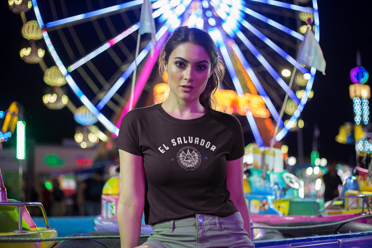 Blue baby tee with El Salvador lettering, emblem graphic, stars, and est. 1821 detail