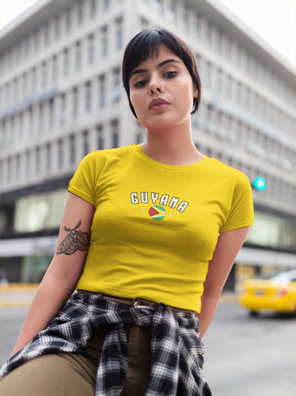 White baby tee with arched Guyana text, circular flag graphic, stars, and est. 1970 detail