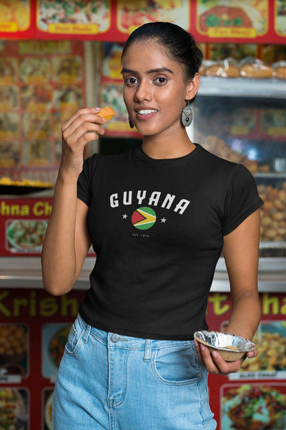 White baby tee with arched Guyana text, circular flag graphic, stars, and est. 1970 detail