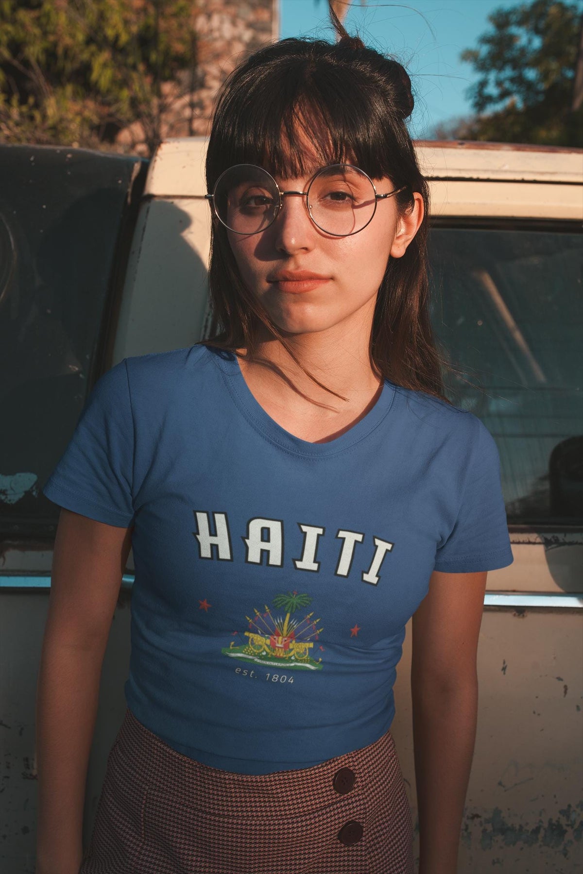 Blue baby tee with arched HAITI lettering, crest-style artwork, stars, and est. 1804 text