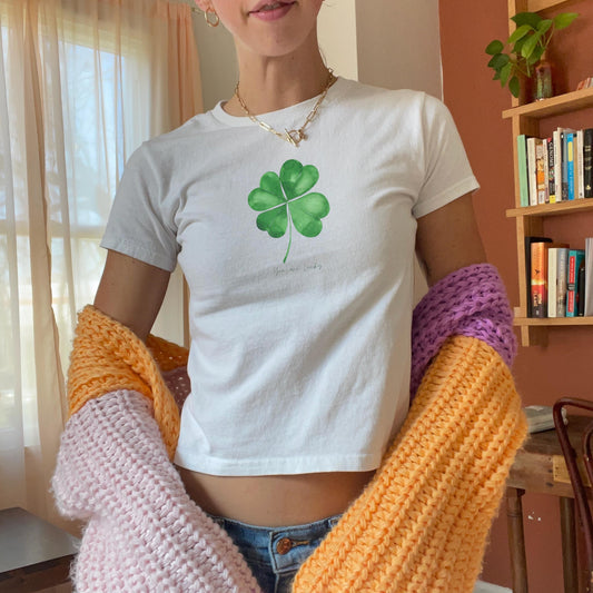 White baby tee with green four leaf clover artwork and small You are lucky text
