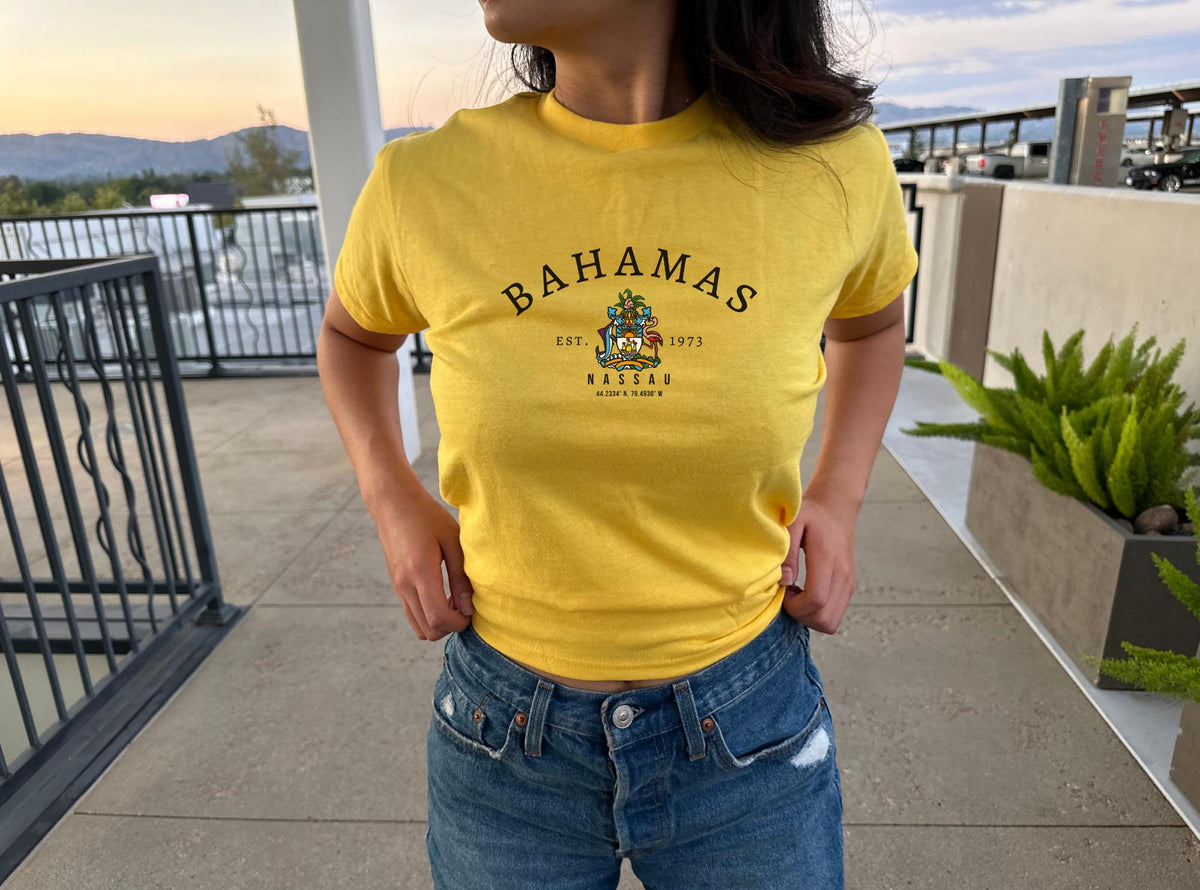 Navy baby tee with arched Bahamas text, crest graphic, Est. 1973, and Nassau lettering