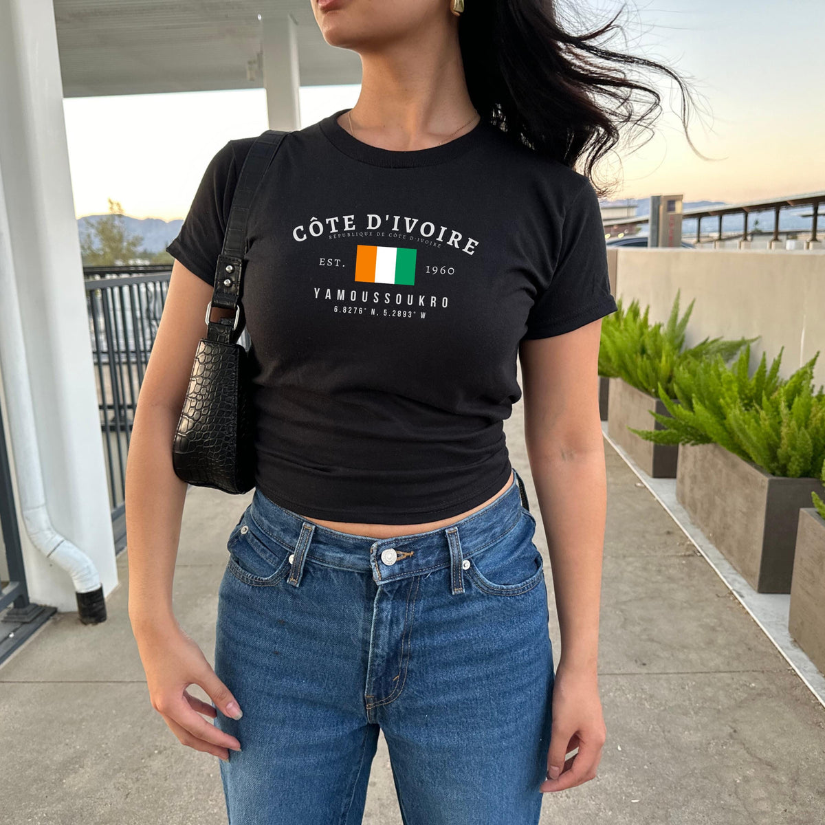 Orange baby tee with Côte d'Ivoire flag, Est. 1960, and Yamoussoukro text design.