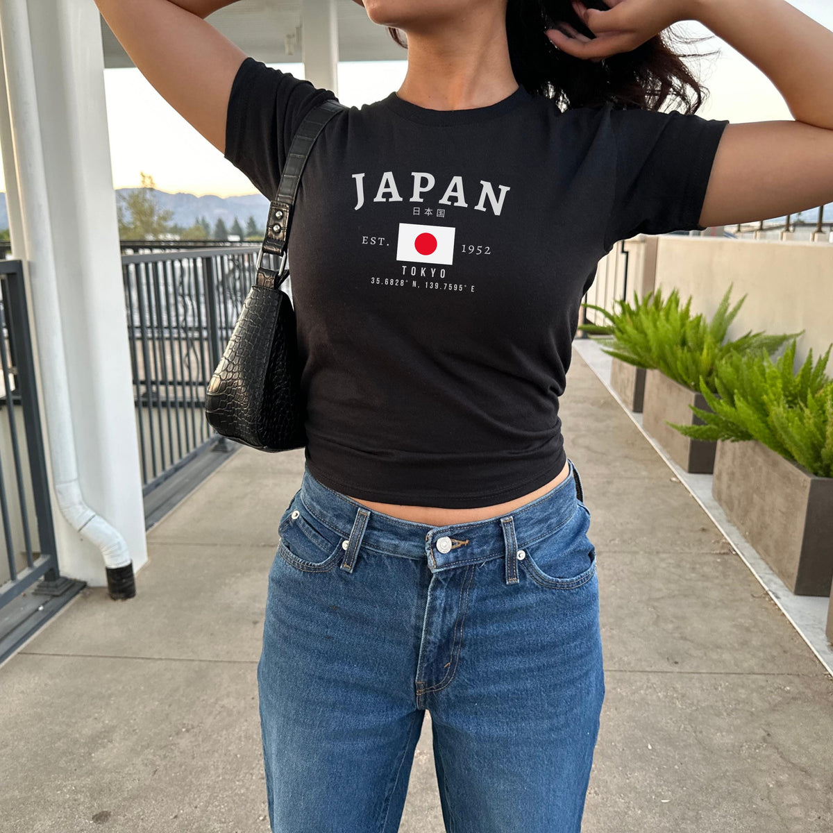 Blue baby tee with JAPAN lettering, Japanese text, Tokyo coordinates, and Japan flag graphic
