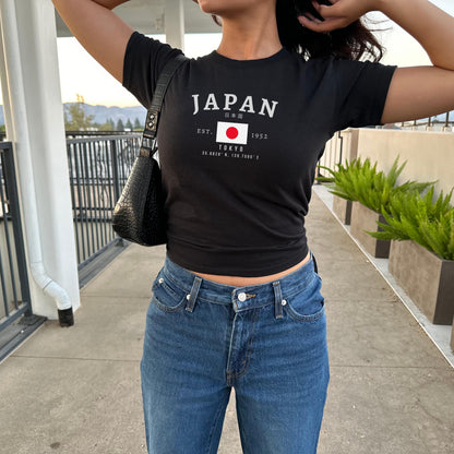 Blue baby tee with JAPAN lettering, Japanese text, Tokyo coordinates, and Japan flag graphic