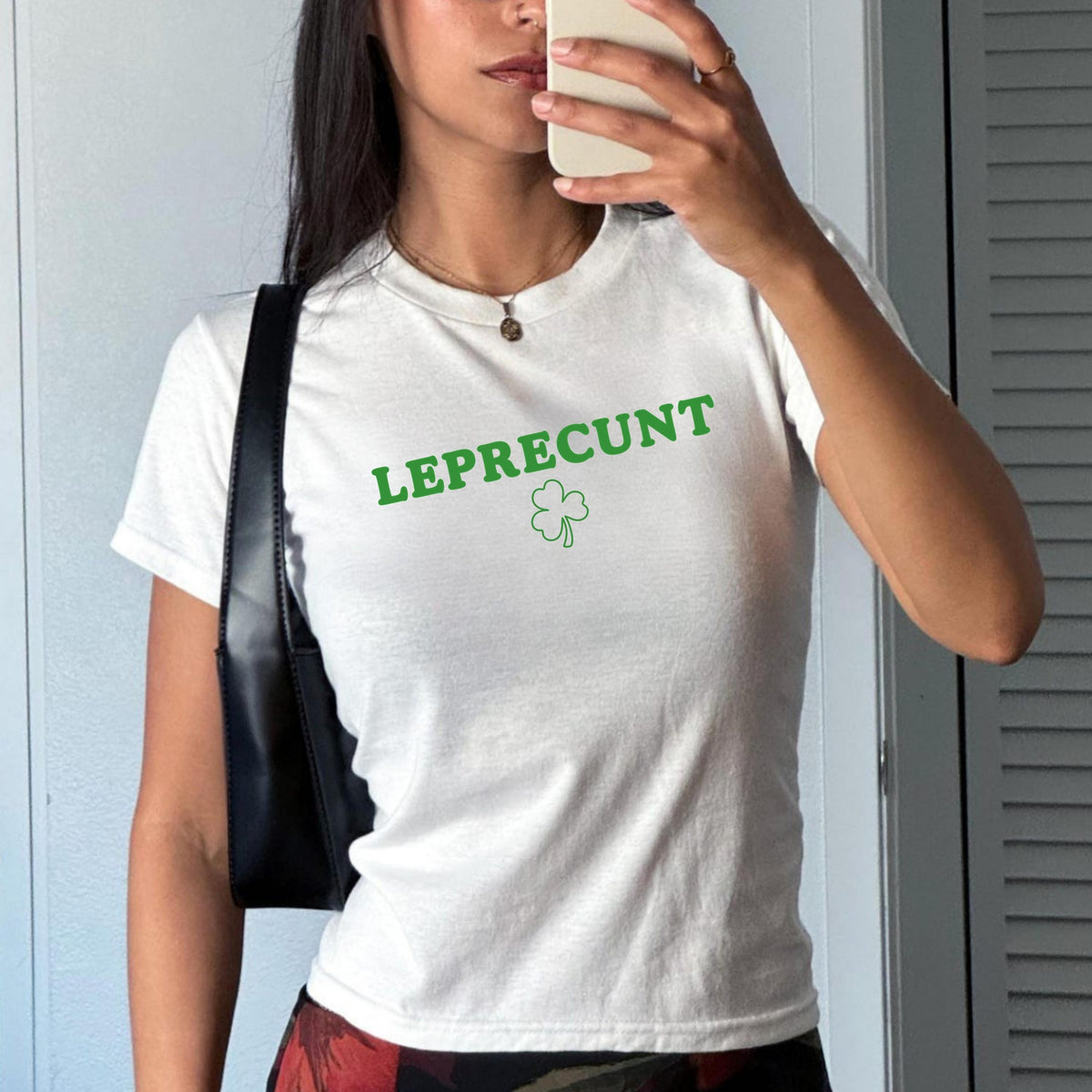 White baby tee with green LEPRECUNT lettering and a shamrock graphic