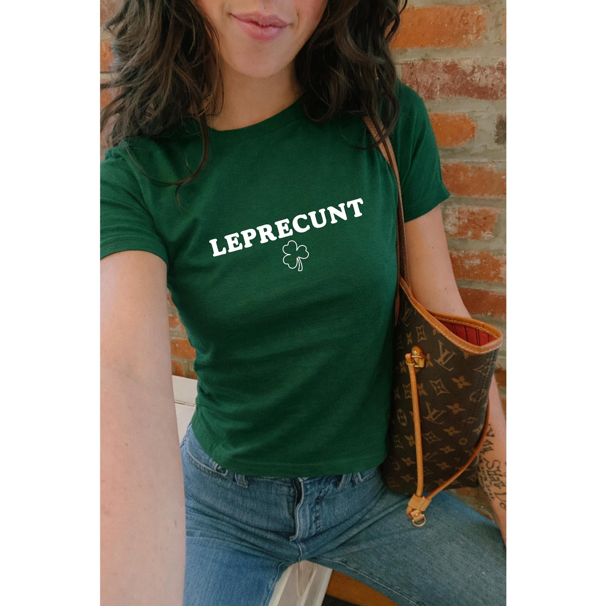 White baby tee with green LEPRECUNT lettering and a shamrock graphic
