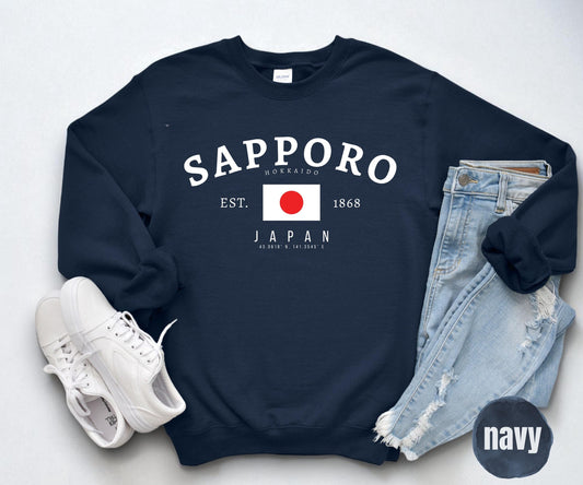 Navy sweatshirt with arched Sapporo Hokkaido Japan text, Japanese flag, EST. 1868, and coordinates