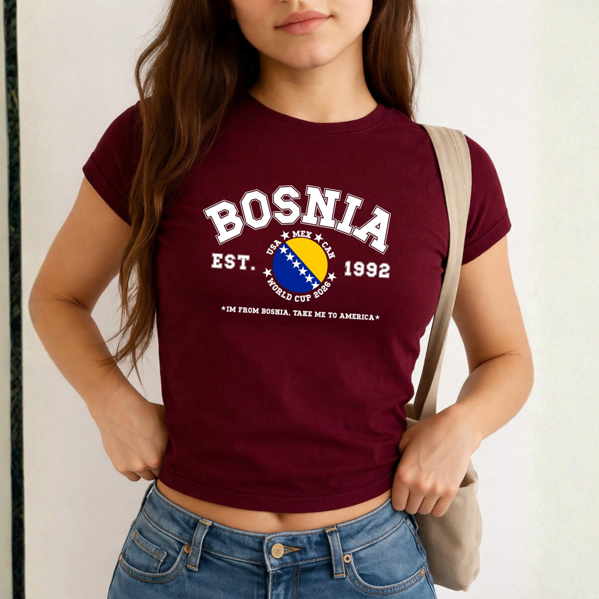 Blue Bosnia baby tee with collegiate flag design, World Cup 2026 text, and take me to America slogan
