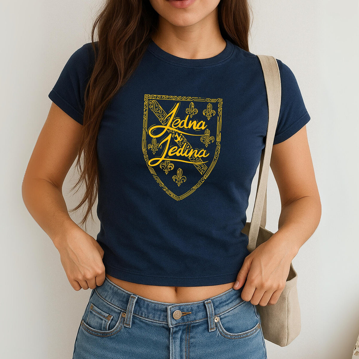 Blue baby tee with yellow Jedina si Jedina shield design and fleur-de-lis details