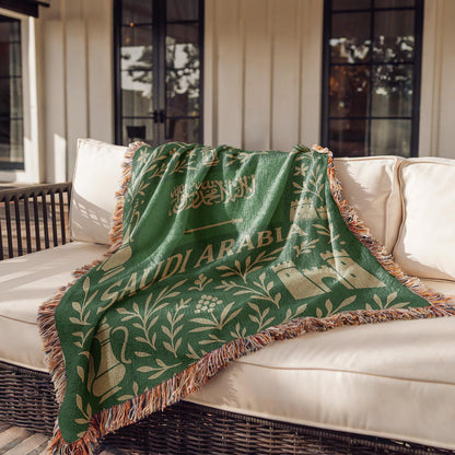 Green Saudi Arabia woven blanket with Arabic script, camel, palm trees, sword, lanterns, and fringe edges