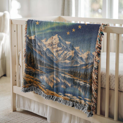 Alaska woven blanket with northern lights, mountain lake scene, gold stars, and fringe edges