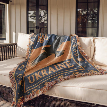 Woven Ukraine blanket with Tryzub trident, flying bird silhouette, folk border, and fringe edges