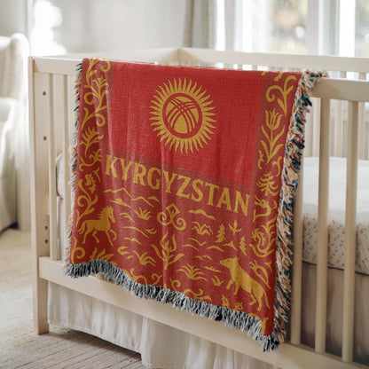 Red and gold Kyrgyzstan woven blanket with horses, mountains, ornamental borders, and fringe edges